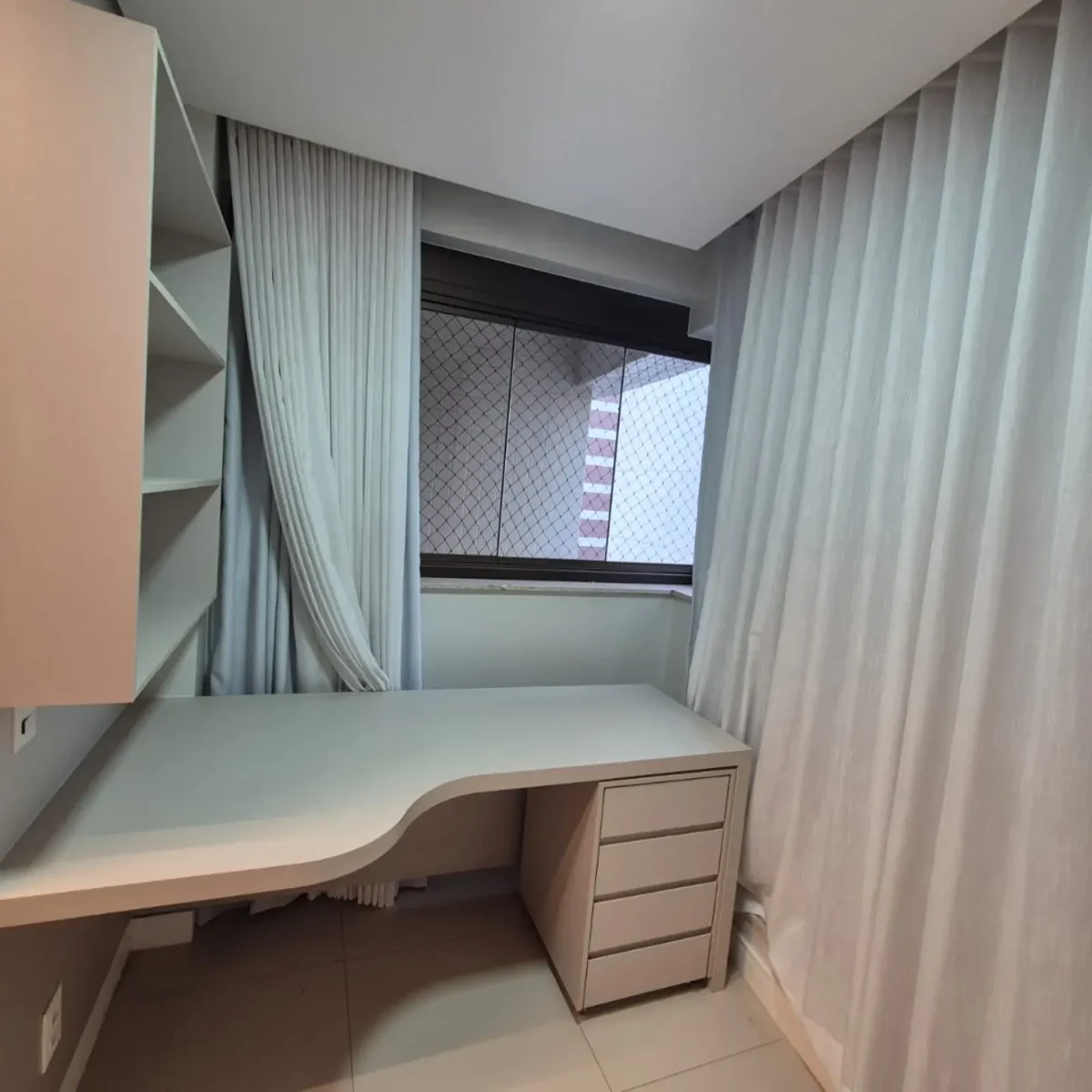 Home office planejado com mesa curva branca, gaveteiro e prateleiras em Brasília - Fábrica Status